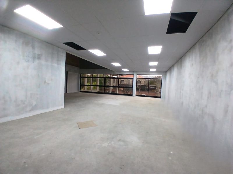An empty, open-plan office space featuring large windows, recessed lighting, and unfinished wall and floor surfaces, ready for custom fit-out.
