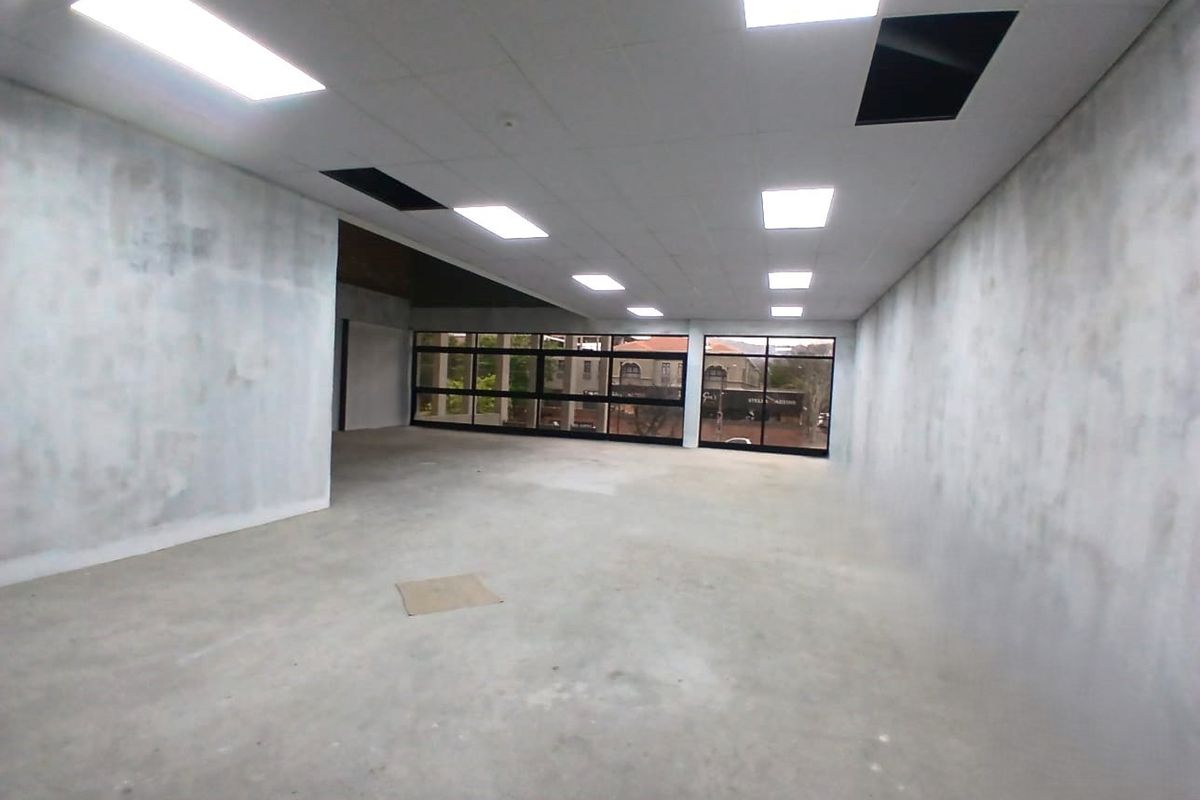 An empty, open-plan office space featuring large windows, recessed lighting, and unfinished wall and floor surfaces, ready for custom fit-out.