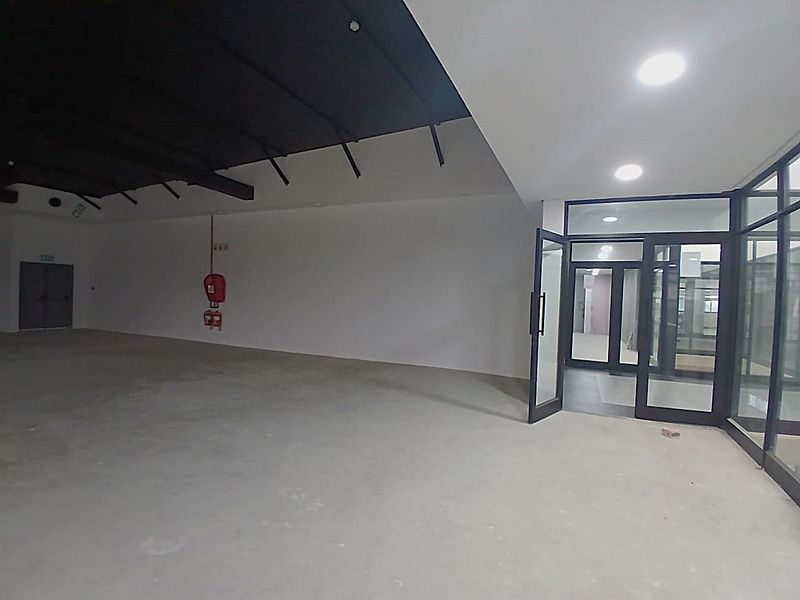 A spacious, open-plan retail unit featuring polished concrete flooring, recessed lighting, and large glass-panelled entrance doors, offering a versatile blank canvas for commercial use.