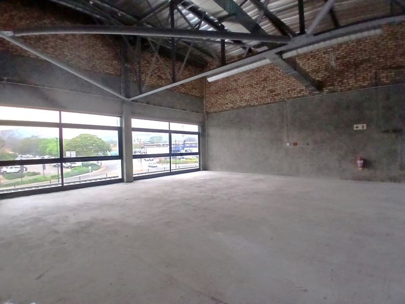 Spacious open-plan retail unit featuring industrial-style exposed brick walls, concrete flooring, and large windows providing ample natural light and street views.