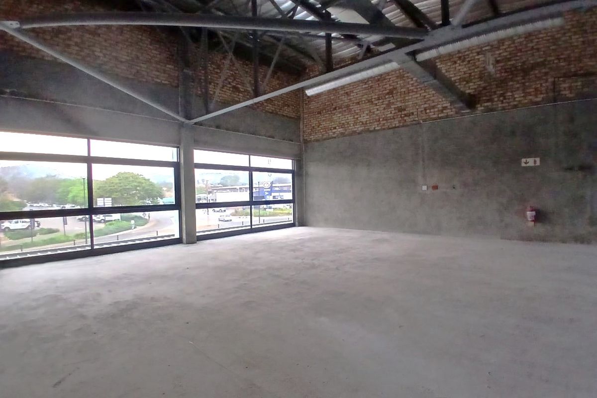 Spacious open-plan retail unit featuring industrial-style exposed brick walls, concrete flooring, and large windows providing ample natural light and street views.