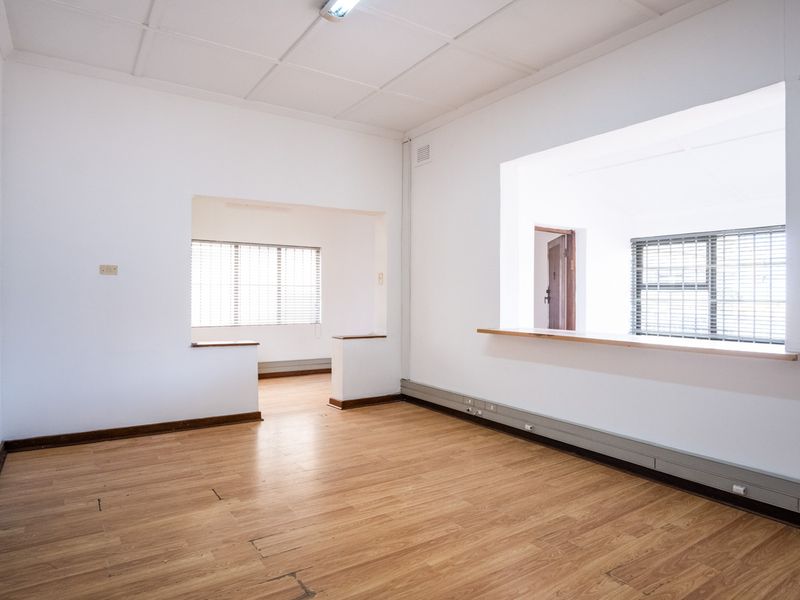 An open-plan office space featuring laminate flooring, drop ceilings, and large window openings with timber sills, providing a bright and functional work environment.