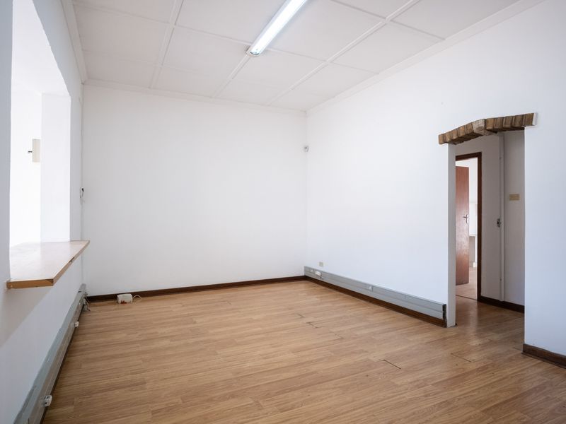 A bright, empty office space featuring laminate flooring, a fluorescent ceiling light, and a timber window sill, ready for professional fit-out.
