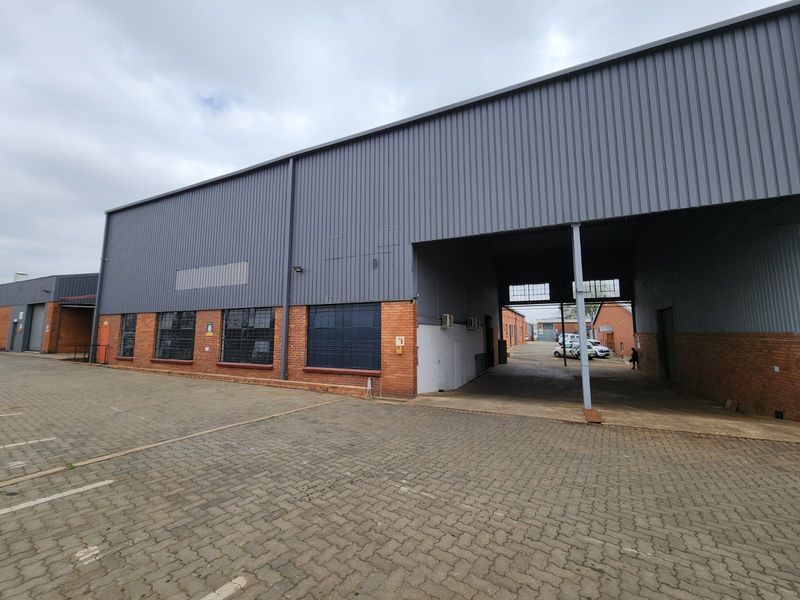 Industrial property exterior featuring corrugated metal cladding, brick masonry, and a large paved driveway with covered access area.