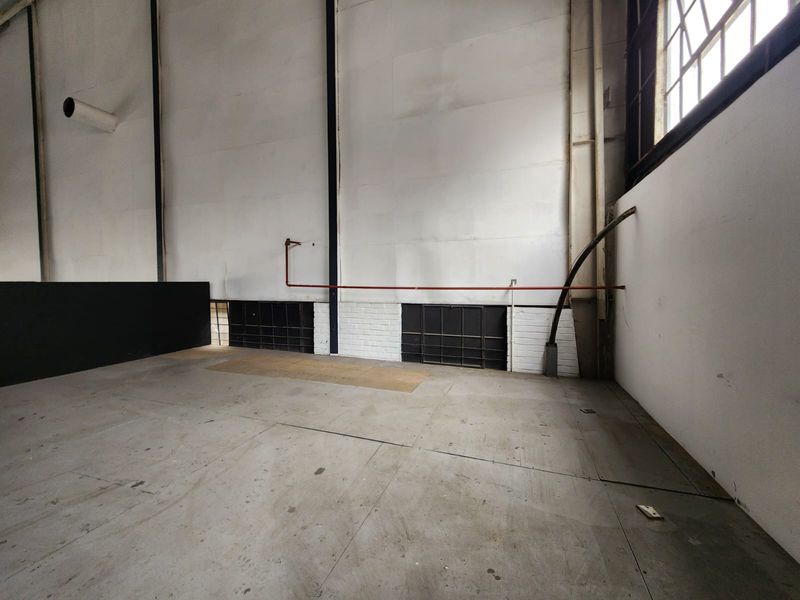 Spacious industrial utility area featuring exposed structural steel, concrete flooring, and high-level industrial windows, suitable for warehouse or workshop use.