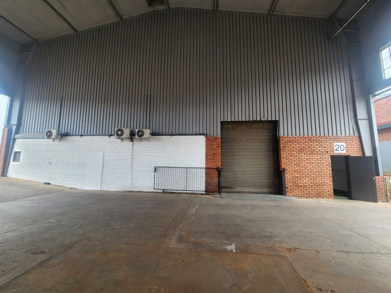 Spacious industrial utility area featuring high-clearance corrugated metal walls, a large roller shutter door, and durable concrete flooring suitable for various commercial operations.