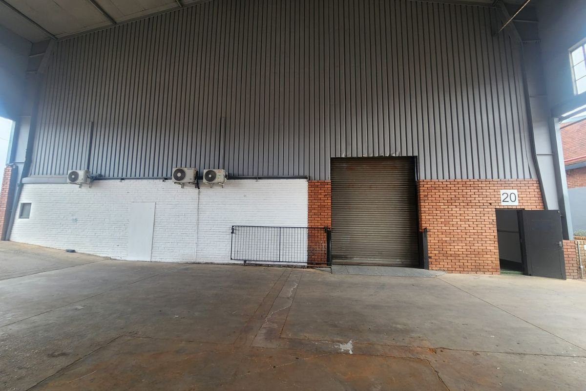 Spacious industrial utility area featuring high-clearance corrugated metal walls, a large roller shutter door, and durable concrete flooring suitable for various commercial operations.