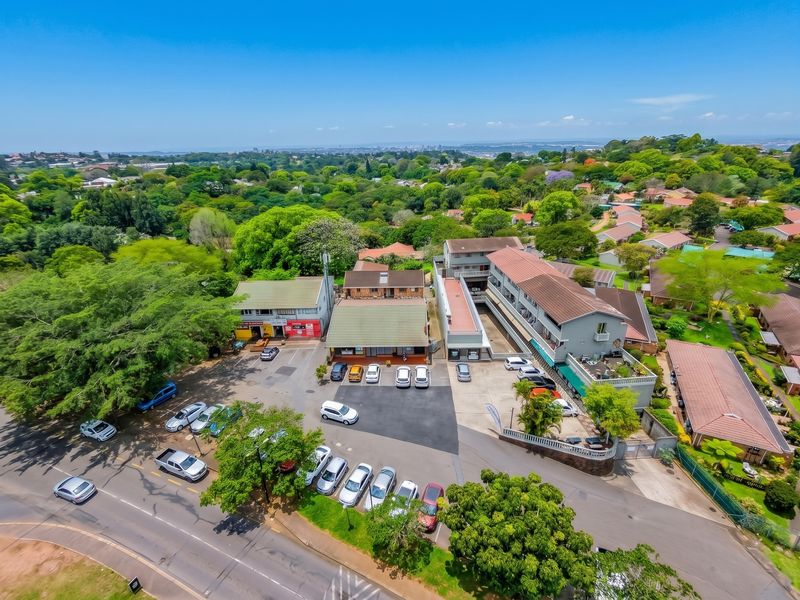 Aerial view of a commercial property complex featuring multiple buildings, extensive paved parking areas, and surrounding landscaped grounds in a suburban setting.