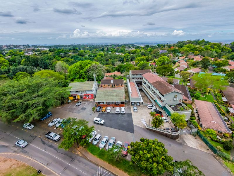 Aerial view of a commercial property complex featuring multiple buildings, extensive parking facilities, and surrounding landscaped grounds in a suburban setting.
