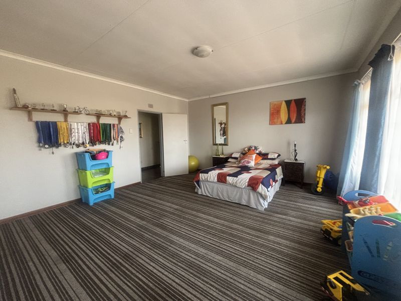 Spacious bedroom featuring fitted carpeting, neutral wall finishes, and a ceiling light fixture, offering a versatile layout for various furniture arrangements.
