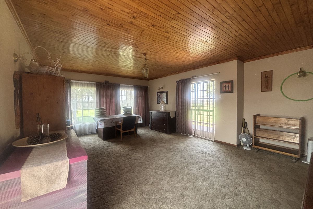 Spacious living area featuring a traditional knotty pine ceiling, carpeted flooring, and direct access to the exterior via a security gate.