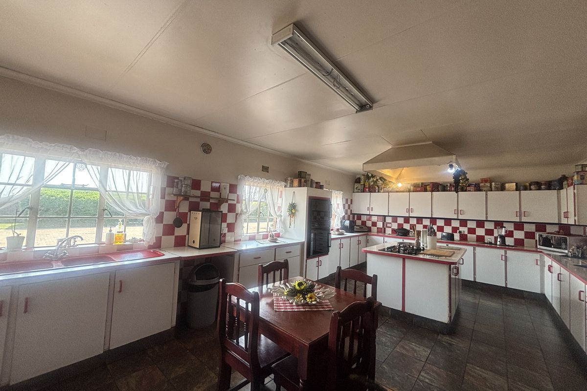 Spacious kitchen featuring extensive built-in cabinetry, a central island with a gas hob, tiled backsplash, and double sink, offering a functional layout.
