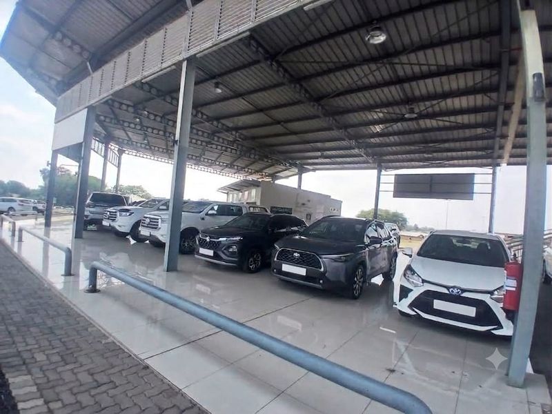 A spacious, covered retail vehicle display area featuring a steel roof structure, tiled flooring, and metal support columns.