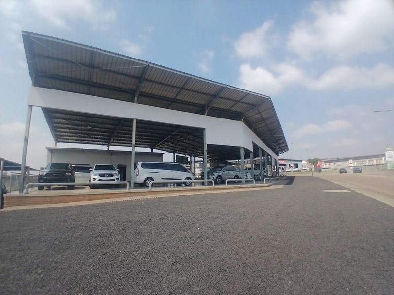 A commercial retail property featuring a large covered outdoor display area with a metal roof canopy and paved driveway.