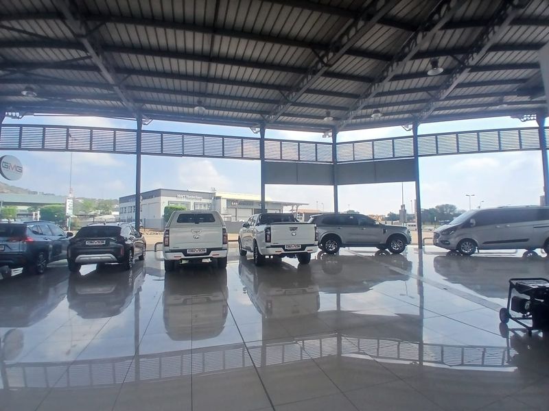 Spacious retail showroom or garage area featuring high steel roofing, polished tiled flooring, and open-plan design with large metal louvre ventilation panels.