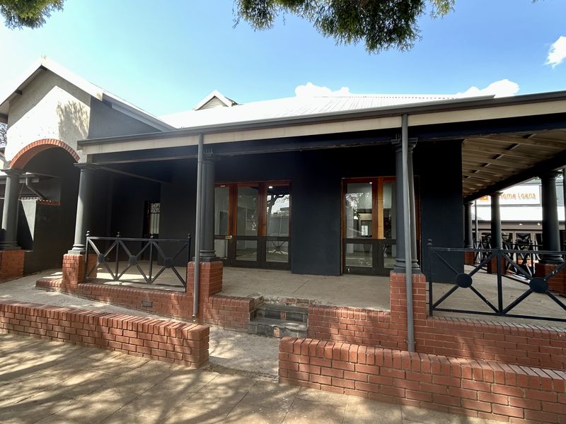 Front facade of a retail property featuring a covered veranda, brick retaining walls, and timber-framed glass entrance doors.