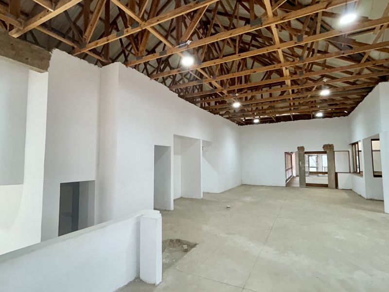 Spacious open-plan retail area featuring exposed timber roof trusses, recessed lighting, and concrete flooring, currently in a shell condition ready for fit-out.