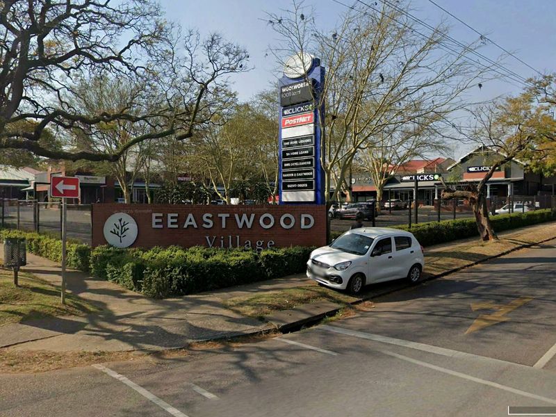 Street view of Eastwood Village retail center featuring prominent pylon signage, perimeter fencing, and landscaped surroundings.