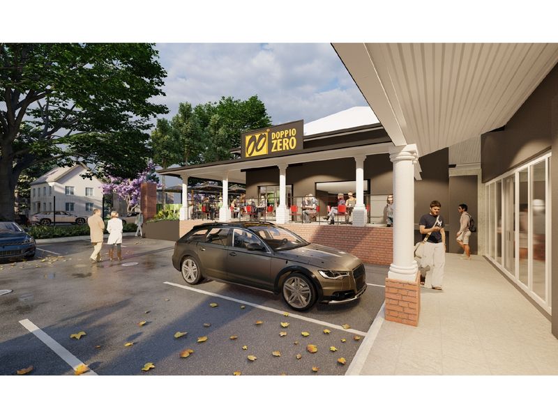 Exterior view of a retail property featuring a covered veranda, brick-based columns, and an adjacent paved parking area.