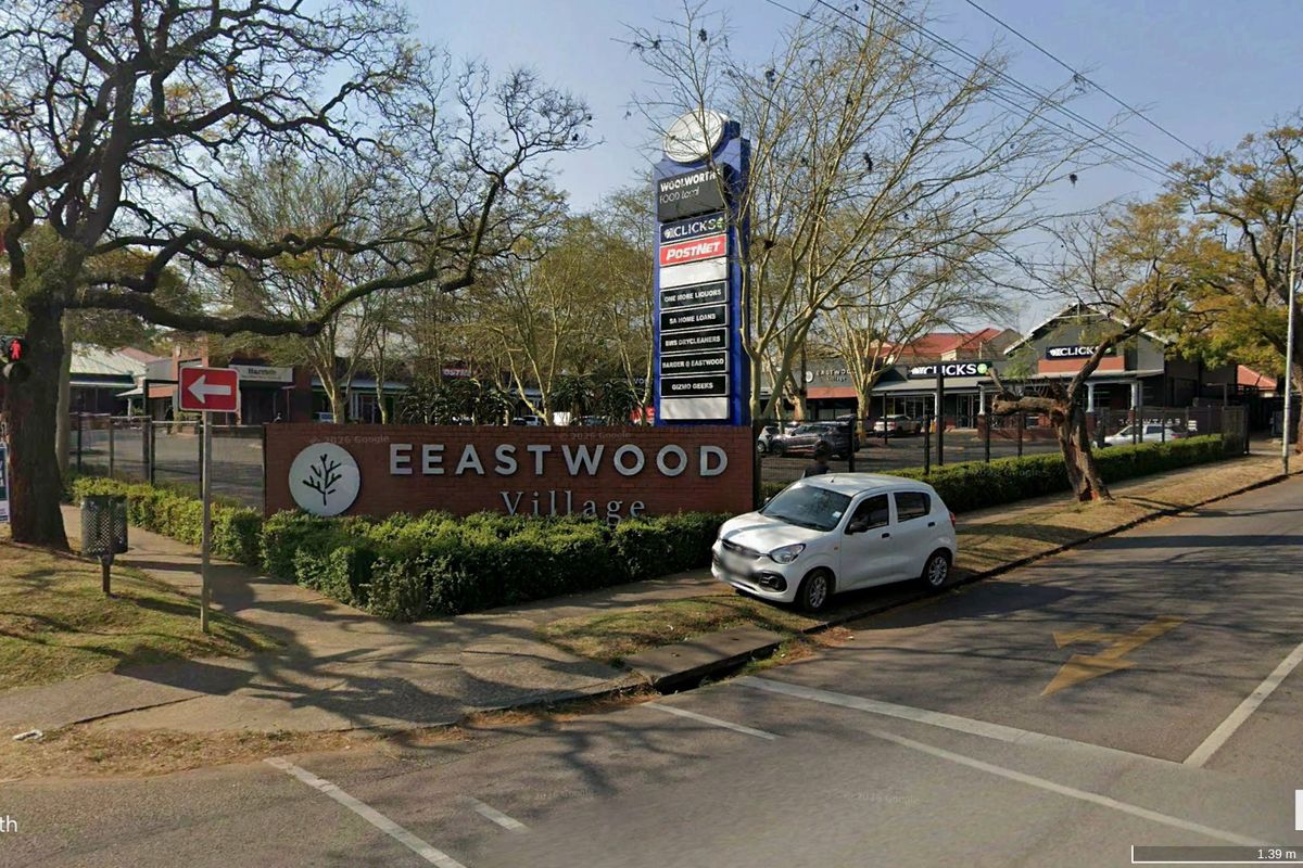 Street view of Eastwood Village retail center featuring prominent pylon signage, perimeter fencing, and landscaped surroundings.