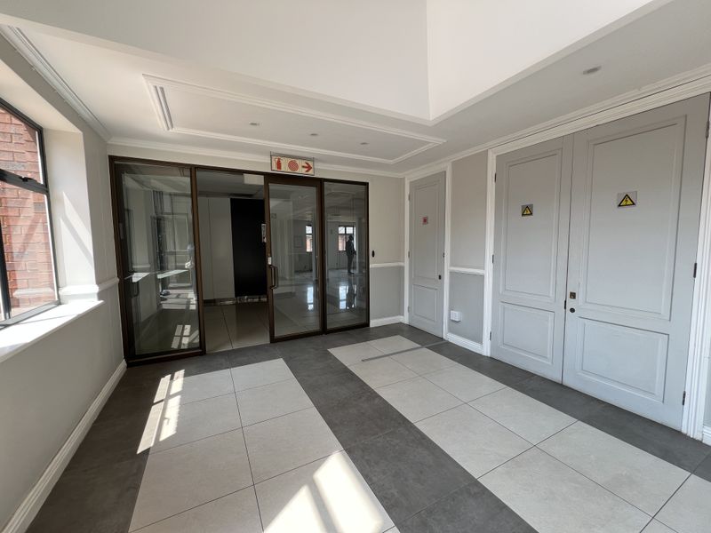 A bright and modern office entrance lobby featuring tiled flooring, glass partitioning, and clean architectural finishes.