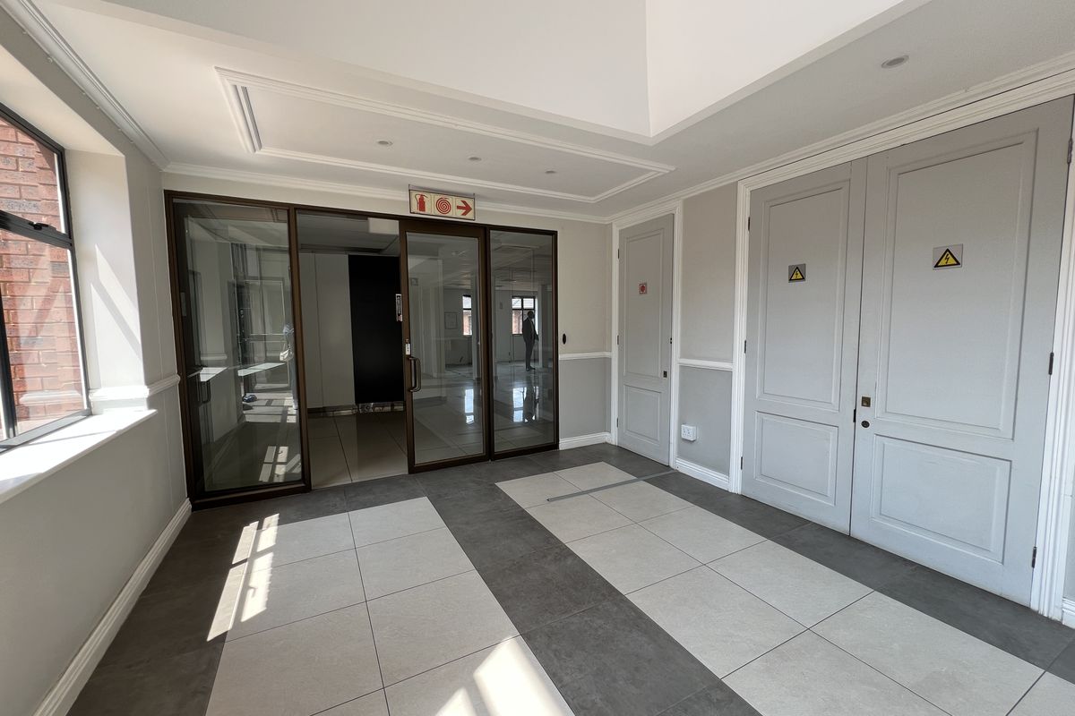 A bright and modern office entrance lobby featuring tiled flooring, glass partitioning, and clean architectural finishes.