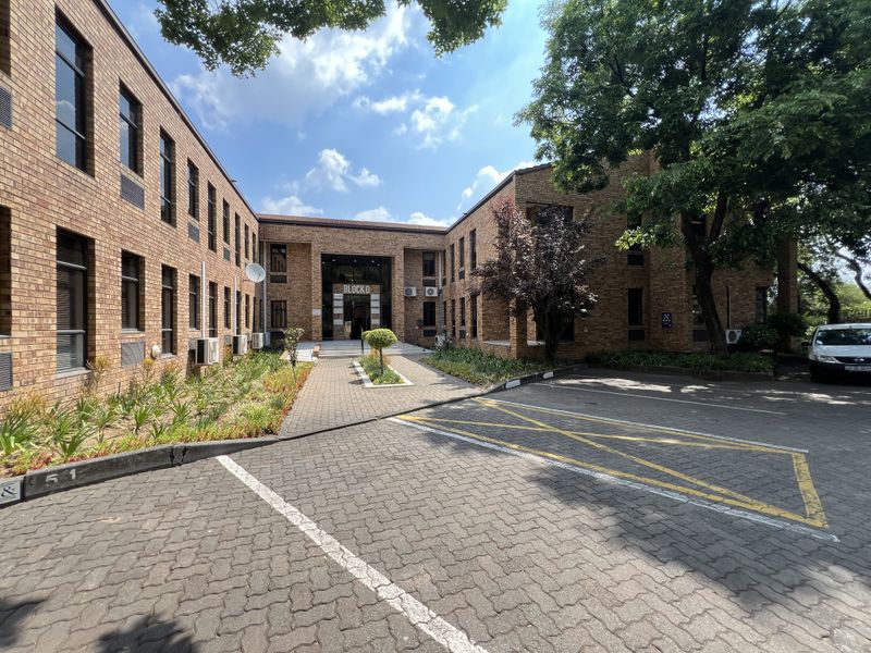 Exterior view of a professional office building, Block D, featuring a face brick facade, paved parking area, and established landscaping.