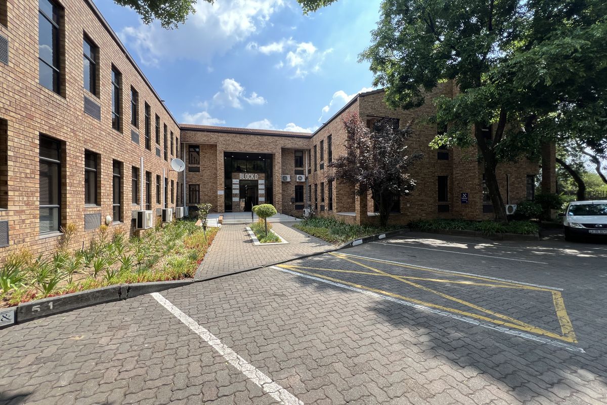 Exterior view of a professional office building, Block D, featuring a face brick facade, paved parking area, and established landscaping.