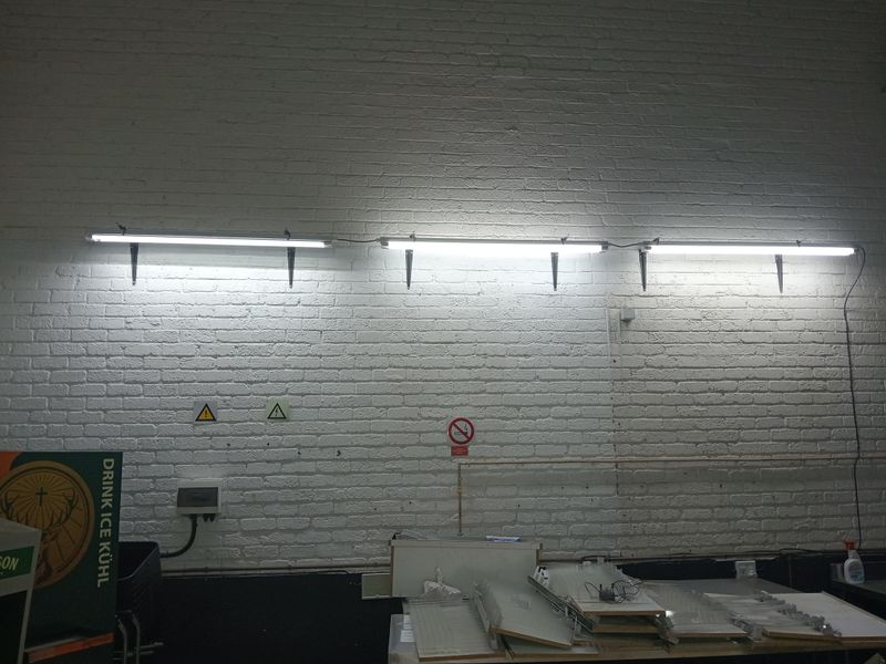 An industrial utility space featuring white painted exposed brick walls and mounted fluorescent strip lighting.