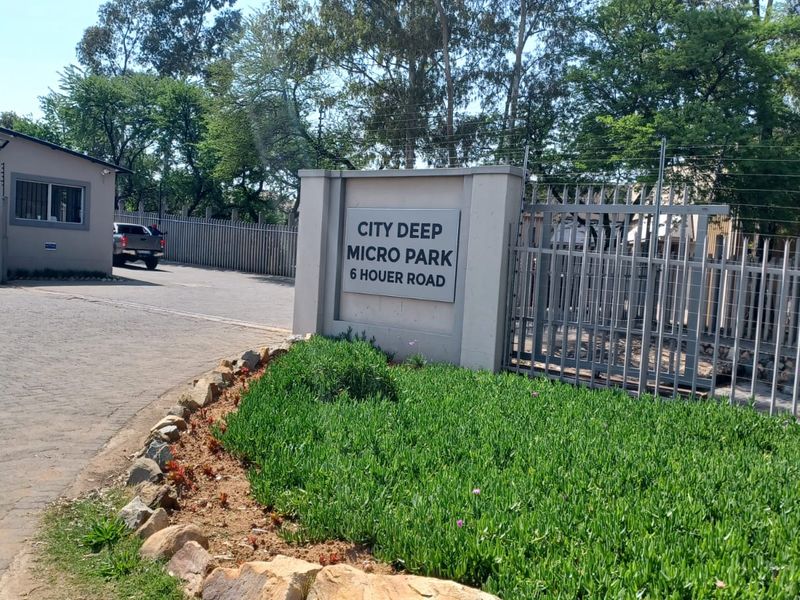 Front entrance view of City Deep Micro Park featuring secure gated access, electric fencing, and paved driveway.