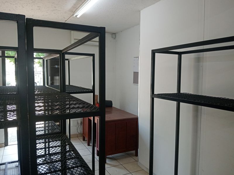 A functional utility or storage space featuring tiled flooring, overhead fluorescent lighting, and an integrated air conditioning unit.