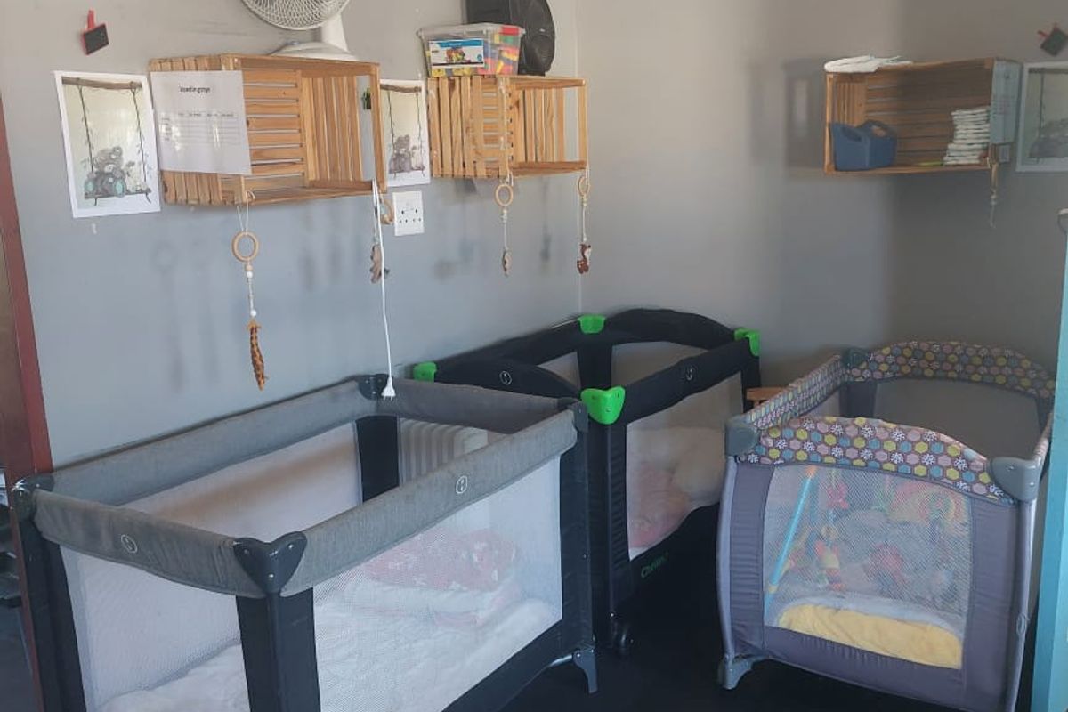 A functional room space currently utilized as a nursery, featuring wall-mounted storage crates and neutral wall finishes.