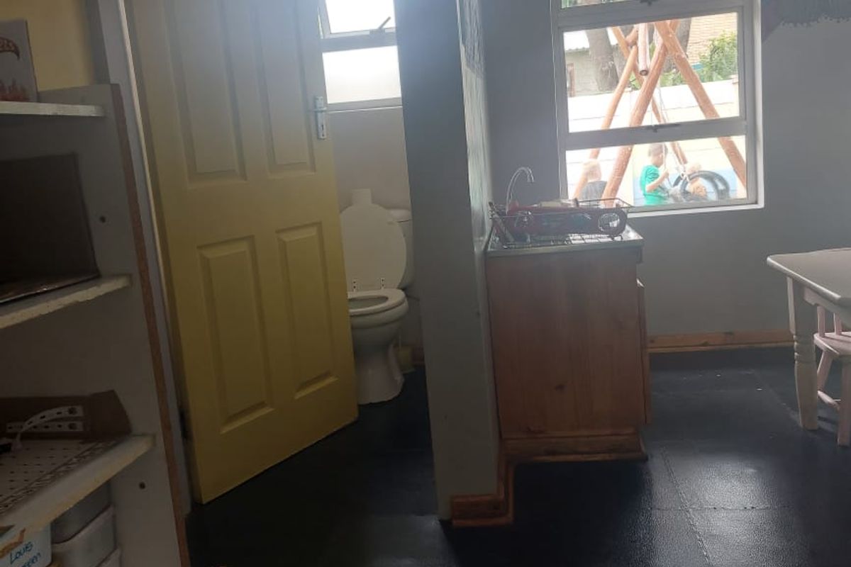 A small bathroom area featuring a toilet and a compact sink unit with cabinetry, showing signs of wear and dated finishes.