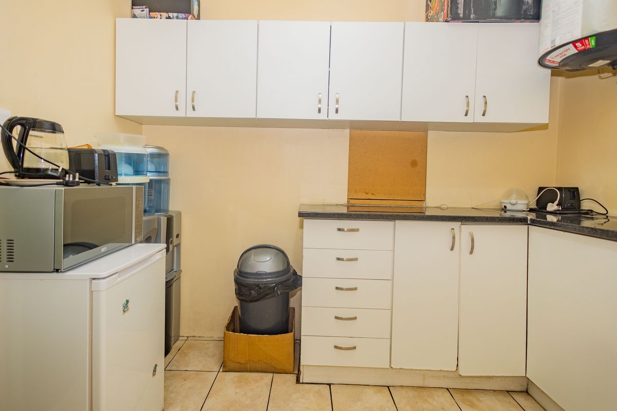 A functional kitchen area featuring white built-in cabinetry, dark laminate countertops, and tiled flooring, providing essential storage and workspace.