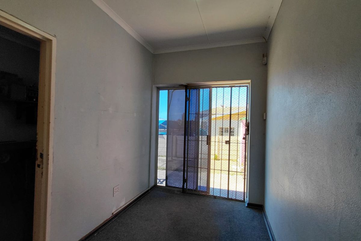 An empty interior room featuring a sliding glass door with security gate, carpeted flooring, and neutral wall finishes.