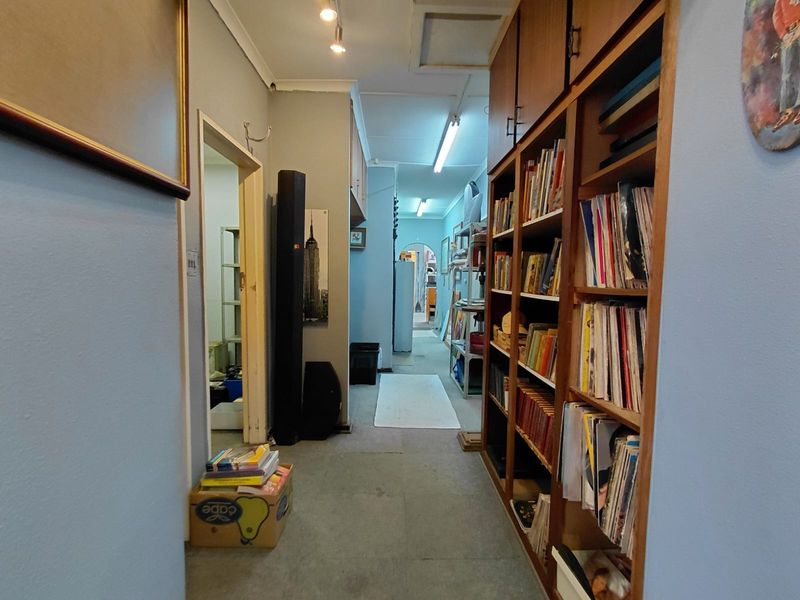 A functional hallway featuring built-in wooden shelving units and direct access to adjacent rooms, providing practical storage and circulation space.