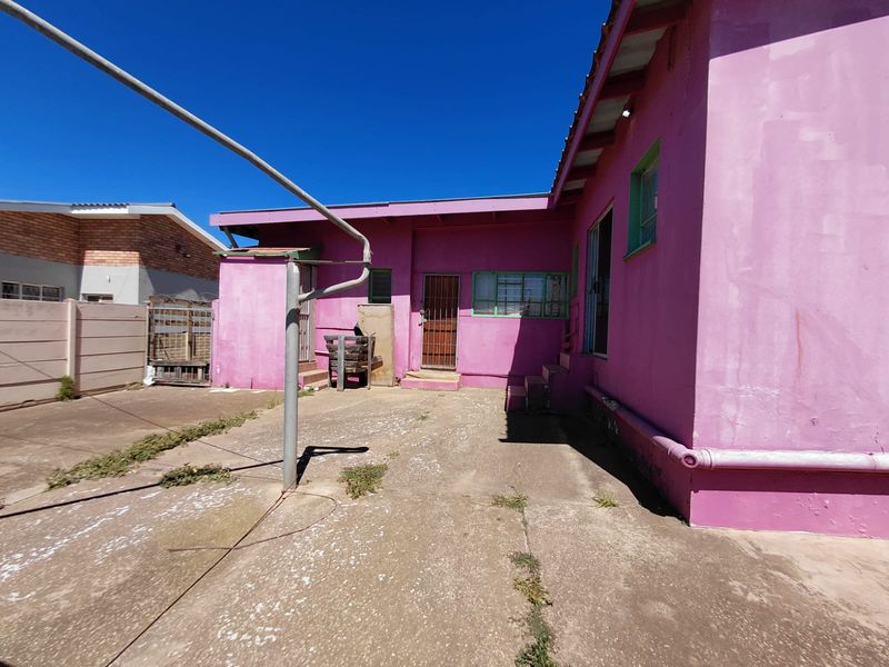 Rear exterior view of the commercial property featuring a concrete courtyard, metal security gates, and painted masonry walls.