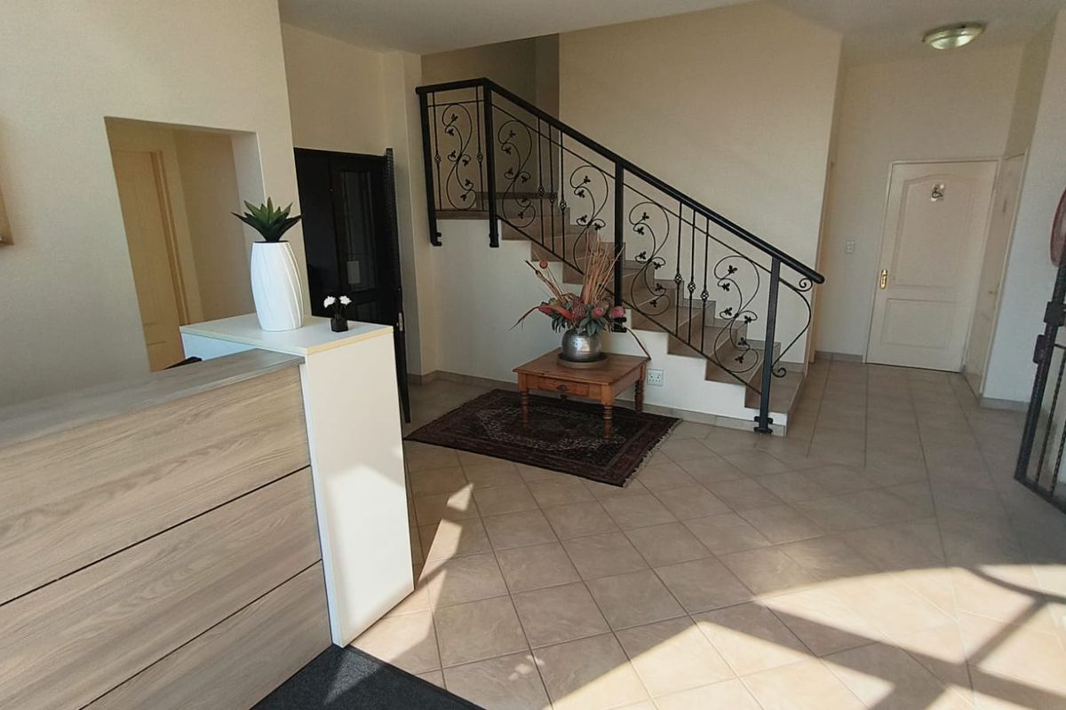 Welcoming office entrance featuring a built-in reception desk, tiled flooring, and an elegant wrought iron staircase leading to the upper level.