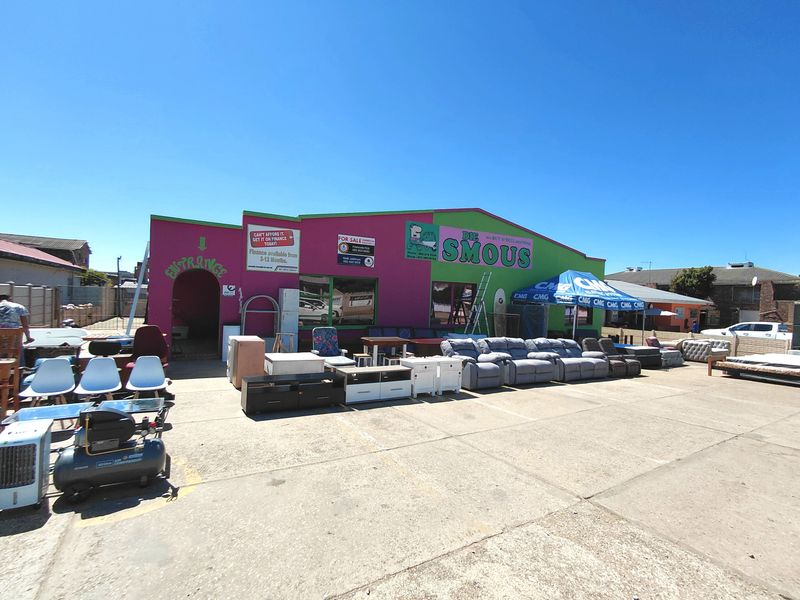 Commercial property exterior featuring a paved frontage, prominent signage, and an entrance area, currently utilized for retail display.
