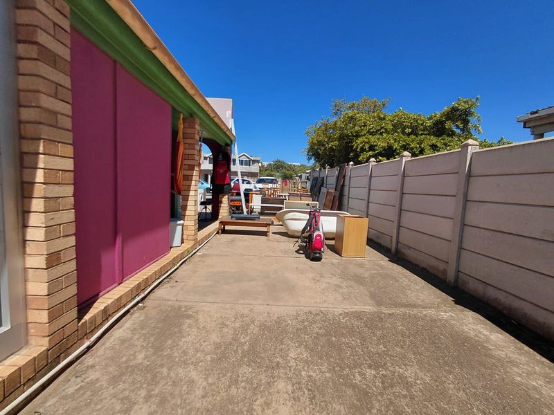 A side exterior area featuring concrete paving, a boundary wall, and access to the building's side facade.
