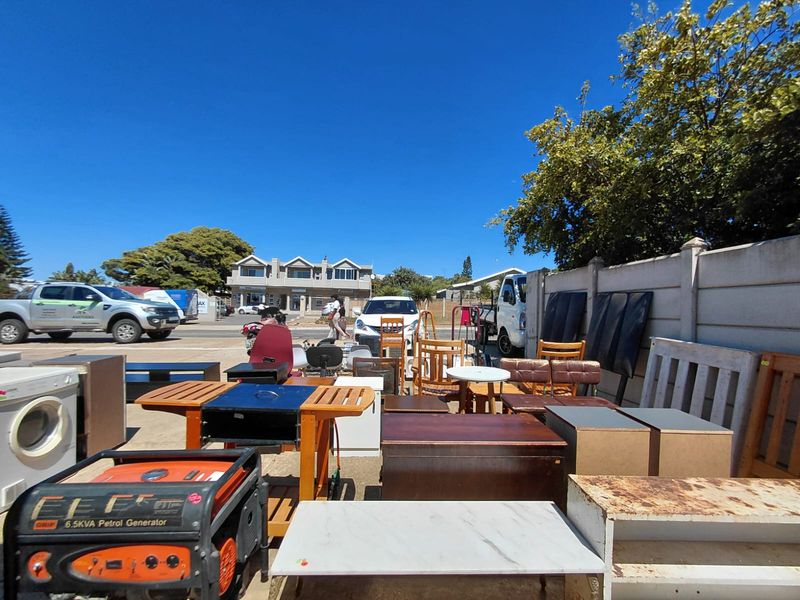 Outdoor commercial yard area featuring a concrete surface and perimeter boundary wall, currently utilized for storage of various items.