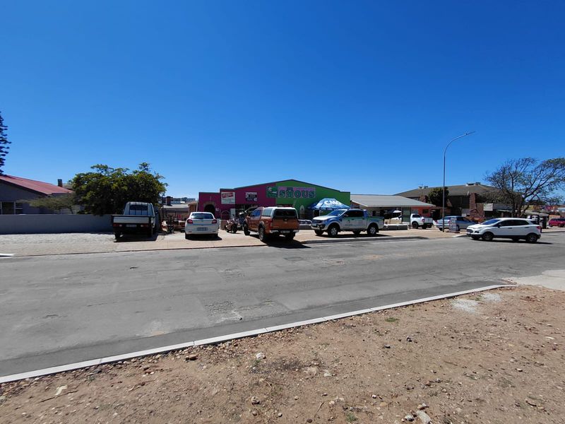 Street view of a commercial property featuring a storefront with signage and an adjacent parking area.