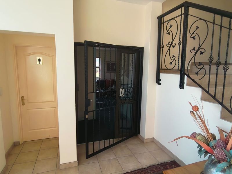 Entrance foyer featuring tiled flooring, a wrought iron security gate, and a staircase with decorative wrought iron railings.