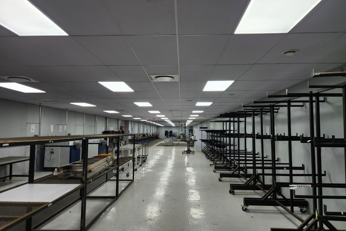 Spacious industrial utility area featuring a suspended ceiling with recessed LED lighting and durable epoxy flooring, suitable for manufacturing or storage operations.