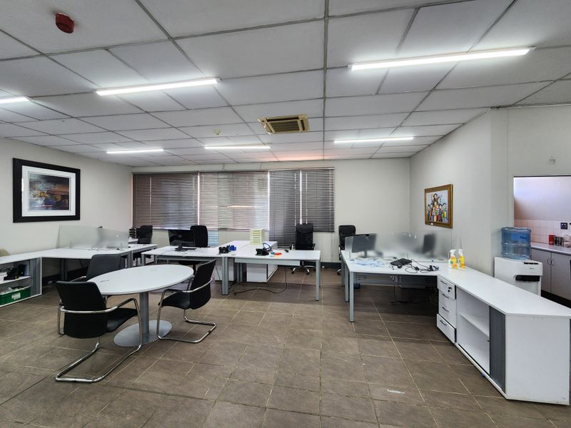 Spacious open-plan office area featuring suspended ceilings, integrated lighting, ducted air conditioning, and tiled flooring with built-in storage cabinetry.