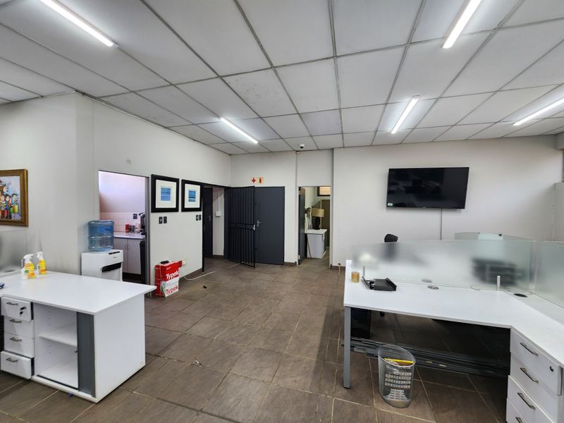 Functional office space featuring suspended ceilings, tiled flooring, and multiple access points to adjacent utility areas.