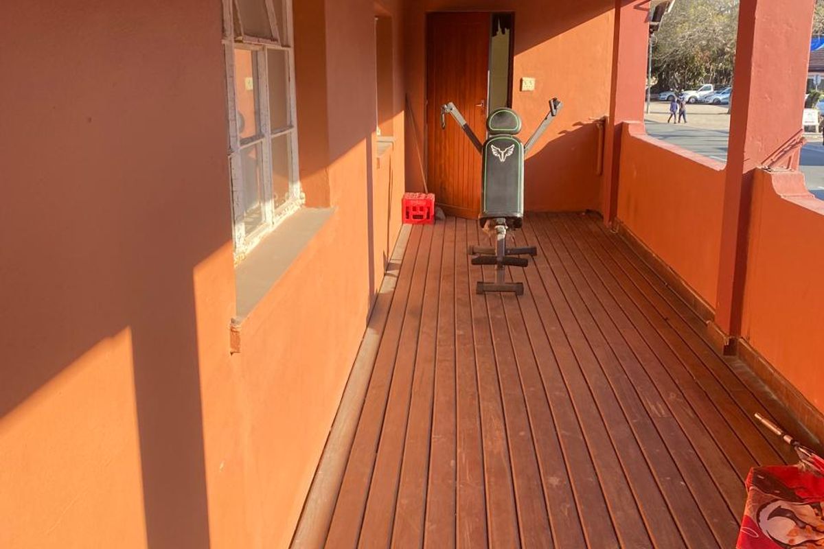 A covered outdoor patio area featuring timber decking, exposed roof beams, and direct access to the building interior.