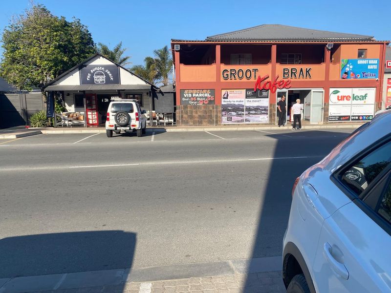 Street-level view of a commercial property featuring a cafe and burger shack with dedicated parking spaces in front.