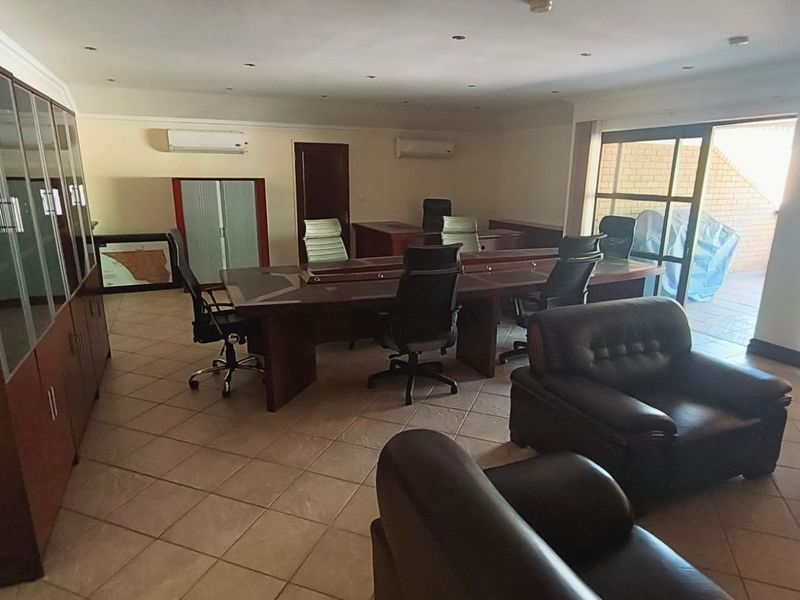 Spacious office area featuring tiled flooring, built-in cabinetry, recessed lighting, and dual split-system air conditioning units with direct access to an outdoor patio.