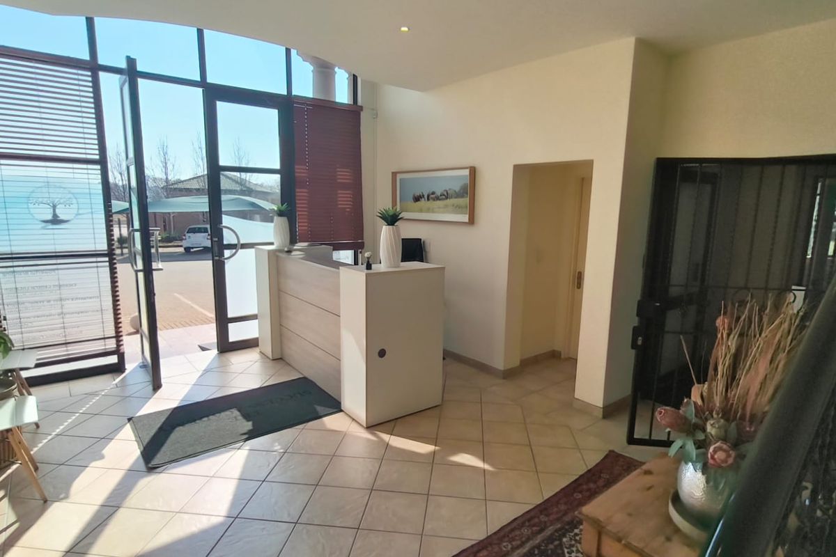 Bright and welcoming office entrance featuring large glass windows, tiled flooring, and a built-in reception desk.